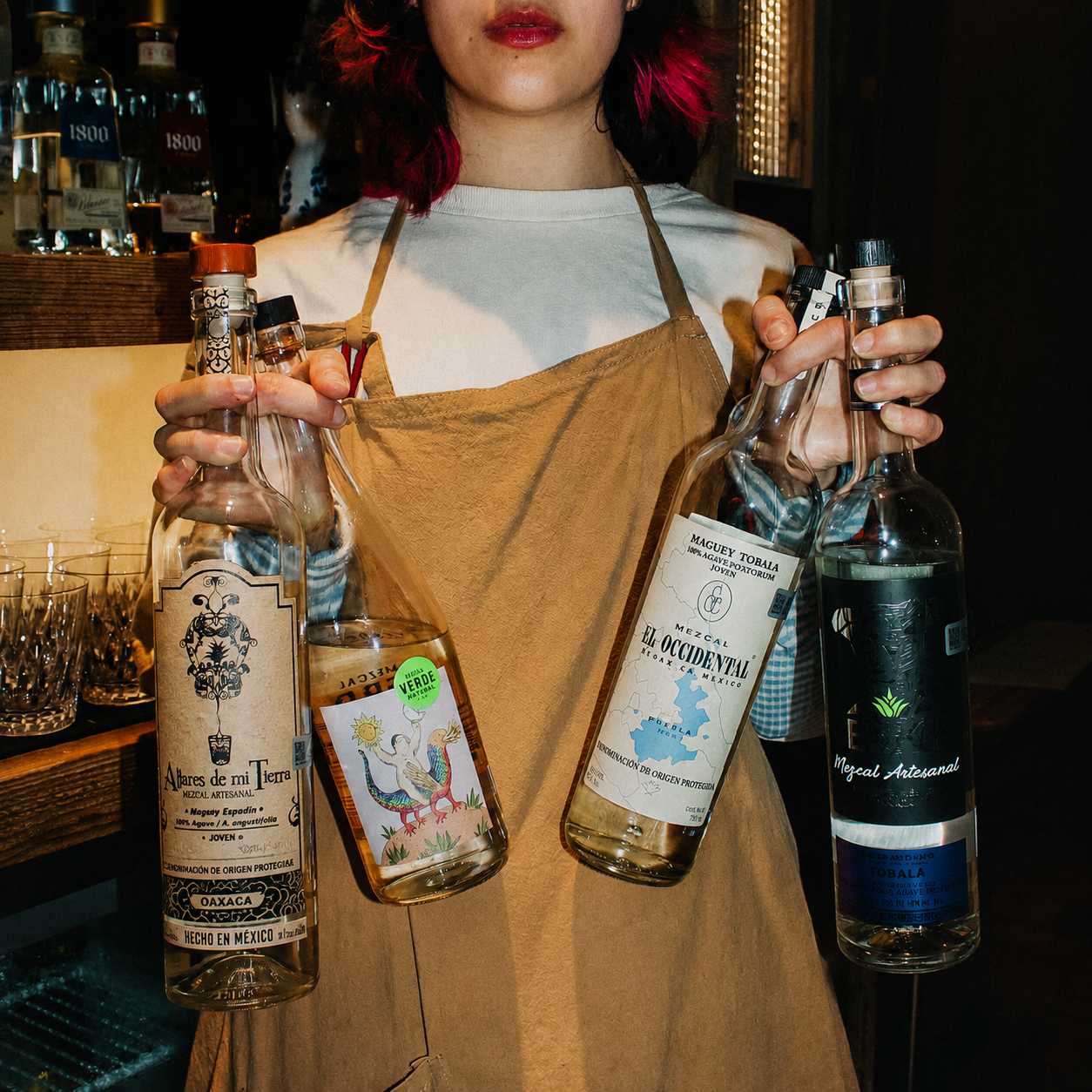Bartender holding mezcal bottles
